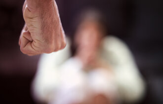 Bildet viser en knytteneve med en person i bakgrunnen som er redd Bildet viser en knytteneve med en person i bakgrunnen som er redd