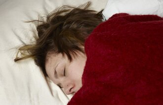 Bildet viser en syk kvinne som ligger i sengen