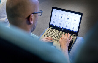 Bildet viser en mann som sitter med PC-en på fanget.