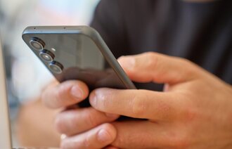 Bildet viser en mann som scroller på telefonen.