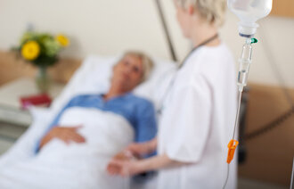 Bildet viser en sykepleier som står ved en pasient