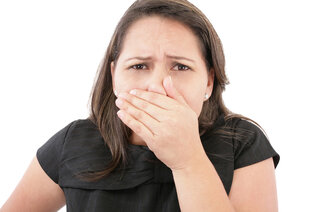 Bildet viser en kvinne som holder seg for nesen og munnen.