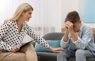 Bildet viser en helsesykepleier som trøster en skolegutt som er lei seg