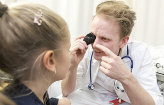 Bilde viser en fastlege som undersøker en liten jente