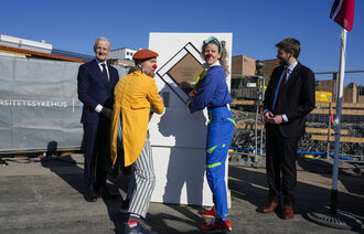 Statsminister Jonas Gahr Støre og helseminister Jan Christian Vestre sammen med sykehusklovnene ved grunnsteinen for det nye Rikshospitalet torsdag.
