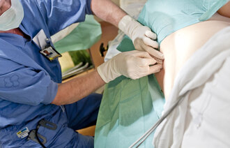 Bildet viser en fødende kvinne som får epidural i ryggen.