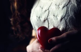 Bildet viser en kvinne som holder opp et hjerte nær brystet.
