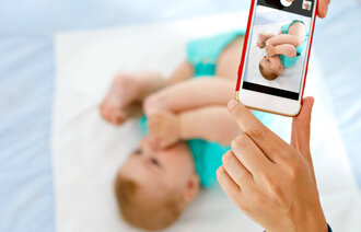 Noen tar bilde av en baby med mobiltelefonen.