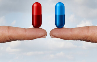 Bildet viser to fingre som holder to forskjellige medikamenter – en rød og en blå pille.