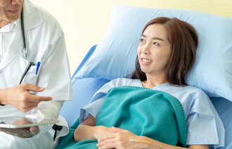Lege på visitt hos kvinnelig pasient i sykeseng