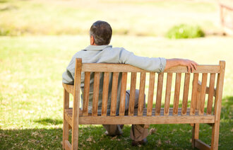 Bildet viser en middelaldrende mann som sitter med ryggen til på en benk.