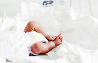 Bildet viser underkroppen til en nyfødt som ligger i kuvøse.