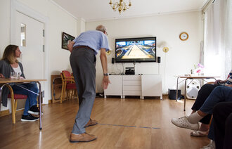 Bildet viser en eldre mann som spiller bowling med Kinect.