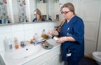 Sykepleier Gjertrud Langnes stikser en urinprøve i pasientens hjem, inne på badet.
