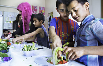 Syriske flyktningbarn lager mat på læresenter i Saida, Libanon
