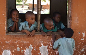 Afrikanske barn som står og ser ut gjennom et åpent vindu