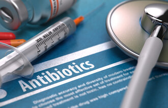 Bilde av sprøyte og antibiotika som ligger på en bakgrunn hvor det står "antibiotika"