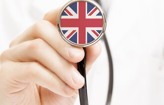 En lege som holder opp stetoskop med det engelske flagget