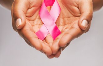 Rosa brystkreftsløyfe som holdes i hender