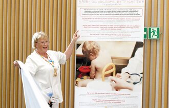 Bildet viser Aud Torild Bjerke som avduker et banner om barns rettigheter på sykehus.