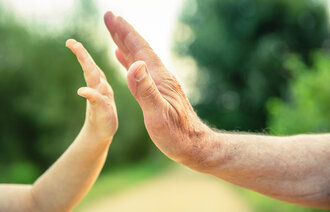 Bildet viser en voksen- og en barnehånd som slår "high five"