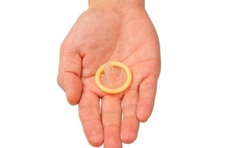Bildet viser en hånd som holder frem et kondom