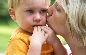 Bildet viser en liten gutt som gråter og som får kyss på kinnet av en kvinne til trøst.