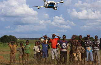 Bildet viser en menneskemengde som ser på en drone som flyr over dem.