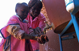 Voksen hjelper barn med håndvask