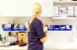 Bildet viser en sykepleier som finner frem medisiner på et medisinrom.