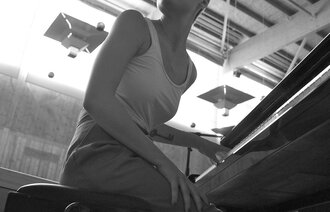 Bildet viser en ung kvinne som sitter ved et piano
