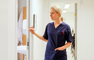 Bildet viser en sykepleier som kikker inn døren til rommet pasienten er på