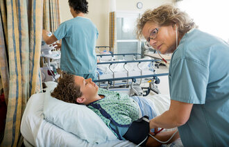Sykepleier tar blodtrykket på pasient.