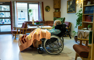 Bildet viser eldre person i rullestol på sykehjem