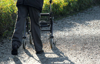 Bildet viser en person som går med en gåstol
