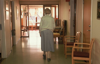 Eldre kvinne går nedover sykehjemskorridor