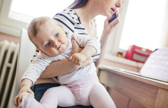 Bildet viser en mor som er mer opptatt av mobiltelefonen enn barnet.