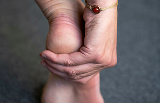Bildet viser en hånd som rører en fot med smerter.