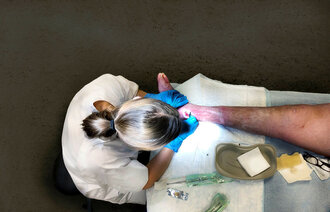 Bildet viser en sykepleier som jobber med et sår.