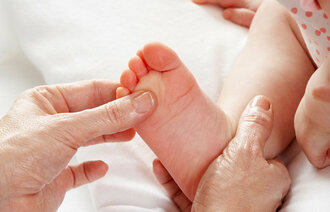 Bildet viser en baby som blir massert på den høyre foten. 
