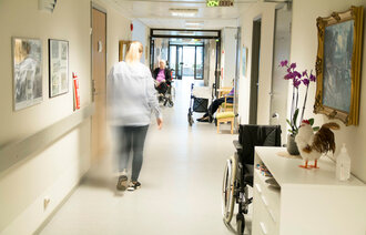 Sykepleier som går nedover en sykehjemskorridor