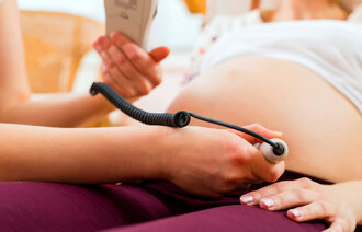 Bildet viser en jordmor som undersøker en gravid kvinne med CTG (kardiotokografi).