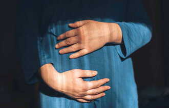 Gravid kvinne med hendene rundt magen.