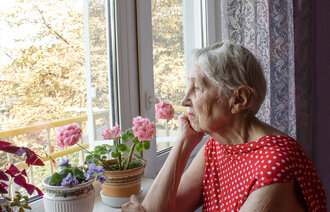 Eldre dame kikker ut av vindu