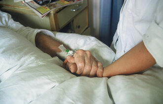Sykepleier holder eldre pasient i  hånden