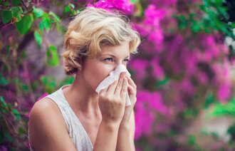 Kvinne med allergi nyser i lommetørkle.