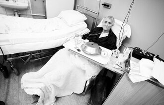 Eldre kvinnelig pasient i sykehusseng