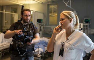 Anette Wiersholm, i sykepleieruniform, snakker i telefonen mens hun blir filmet.