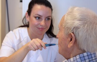 Bildet viser en sykepleier som pusser tennene til en eldre mann
