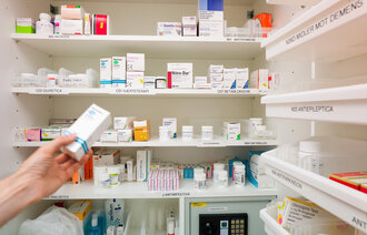 Bildet viser et medisinrom og en hånd som tar en eske tabletter